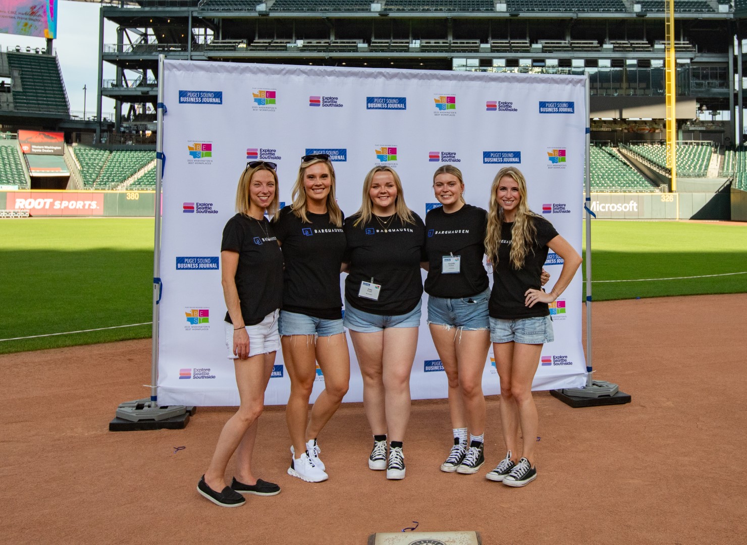 Group of people standing in front of a backdrop on a baseball field